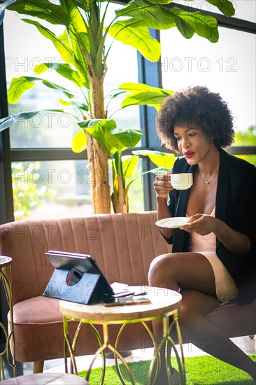 Black skinned girl with afro hair wearing a pink dress and black jacket