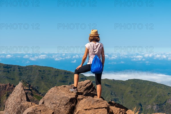 A young woman at the Miradouro do Juncal on Pico do Arieiro and its mountains