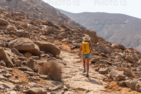 A hiker with a yellow backpack walking along the canyon path towards the Mirador de la Penitas