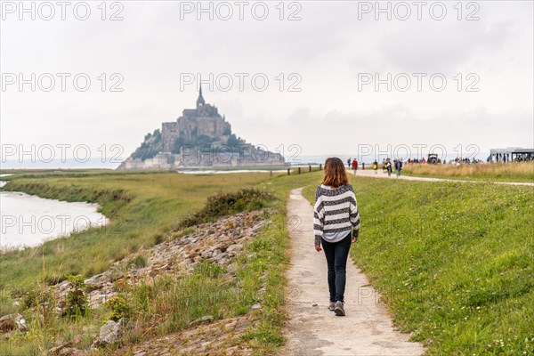 A young tourist walking from Point de Vue towards the Abbey of Mont Saint-Michel