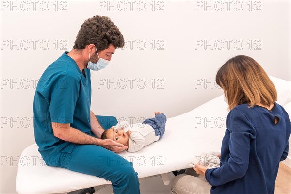 Profile photo of a doctor examining a newborn baby in a clinic next to his mother