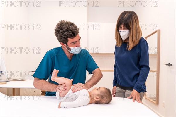 Frontal photo of a young doctor and mother during a baby check up in a clinic