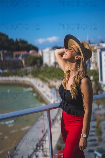 Portrait of a blonde woman spending her holidays in a luxury hotel on a terrace wearing a hat