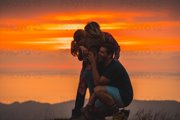 A family hugging and having fun on the top of a mountain at sunset. Adventure lifestyle A summer afternoon in the mountains of the Basque country