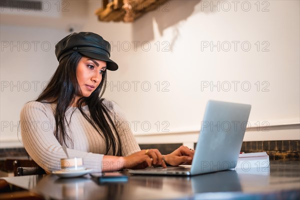 Latin fashion designer making some designs in a cafeteria with her laptop