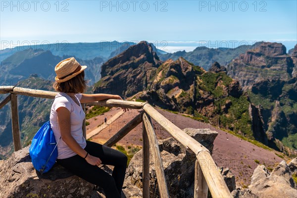 A tourist sitting looking at the mountains in the mountains at Pico do Arieiro