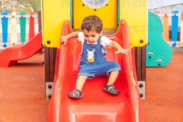 Boy playing in a playground having fun in summer and getting off the squeaker