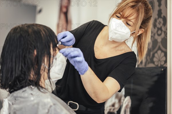 Cutting the bangs to a client with security measures. Reopening with security measures of Hairdressers in the Covid-19 pandemic