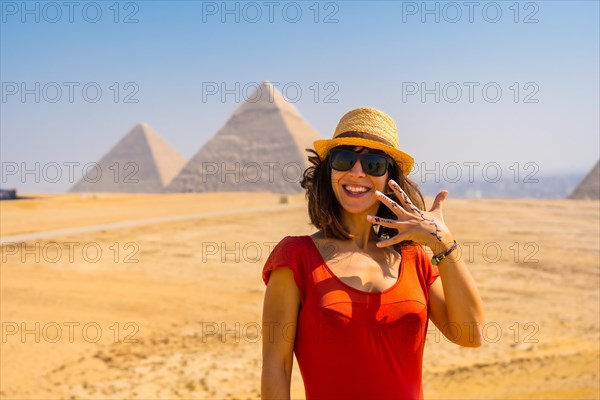 Portrait of a young tourist in red dress enjoying the pyramids of Giza