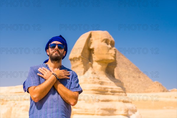 A young tourist near the Great Sphinx of Giza dressed in blue and a blue turban