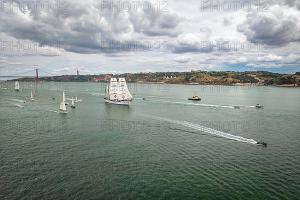 Aerial drone view of tall ships with sails sailing in Tagus river towards the Atlantic ocean in Lisbon