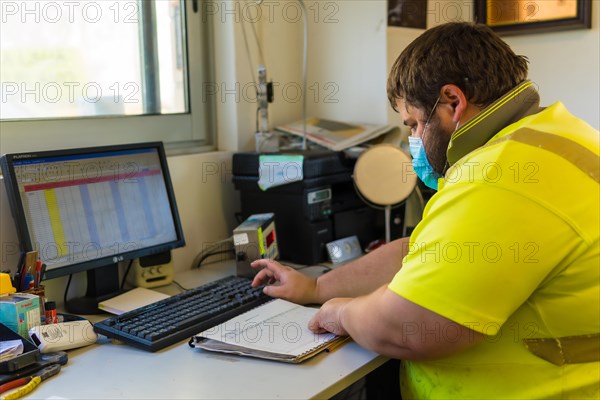 Worker in a recycling factory or clean point and garbage with a face mask and plastic protective screen