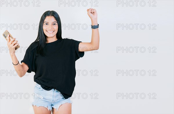 Happy teen girl celebrating with phone isolated. Happy people holding smartphone and celebrating. Winner happy young girl holding cell phone