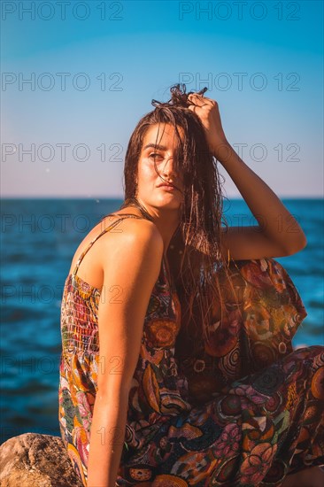Portrait of a young Caucasian woman from the back with wet hair and a floral dress by the sea