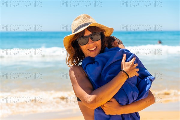 Mother hugging her son by the sea on vacation