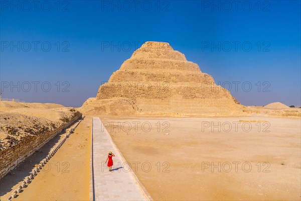 A young woman in a red dress visiting the Stepped Pyramid of Djoser