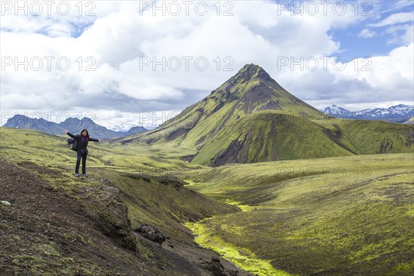 A young woman on a green mountain and a beautiful river of moss on the 54 km trek from Landmannalaugar