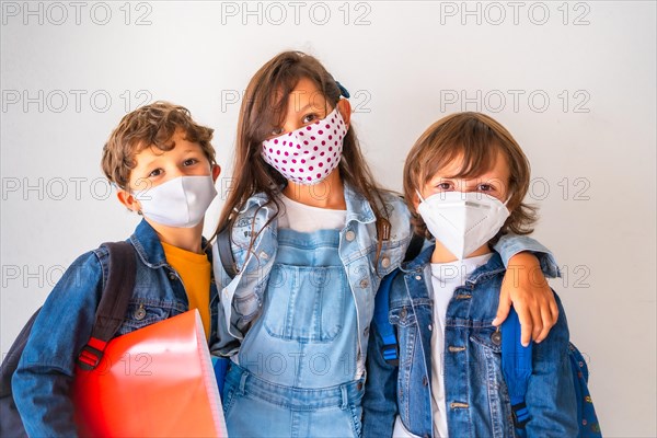 Three children with face masks ready to go back to school. New normality