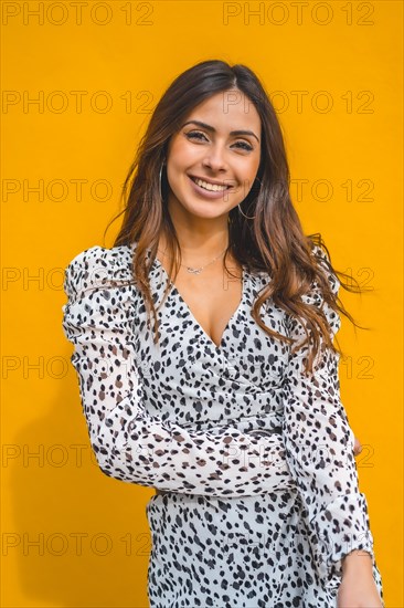 A pretty brunette smiling with a yellow background behind