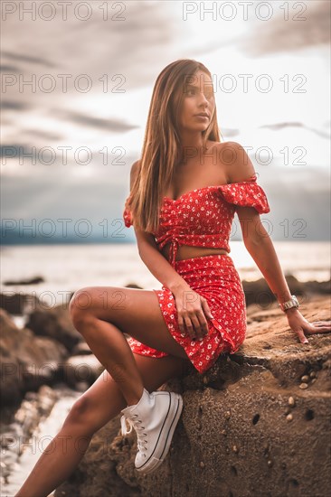 A young brunette Caucasian woman in a red dress on the beach of Itzurrun in the town of Zumaia