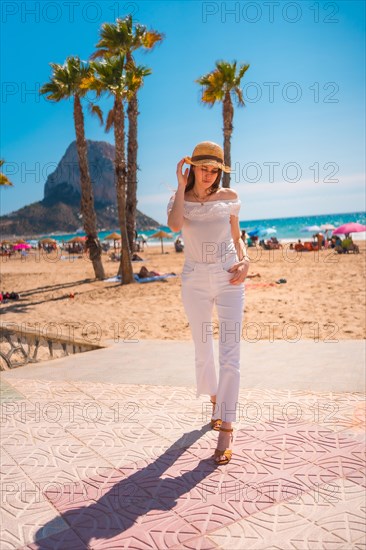 A red-haired Caucasian dressed in white and with a straw hat in the town of Calpe