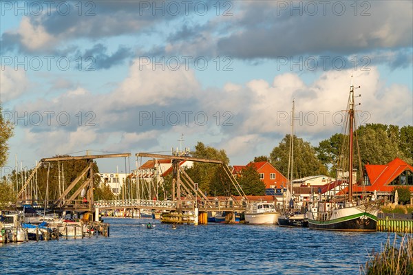 Historic Wieck wooden bascule bridge over the river Ryck and sailing ships in the harbour of the fishing village Wieck