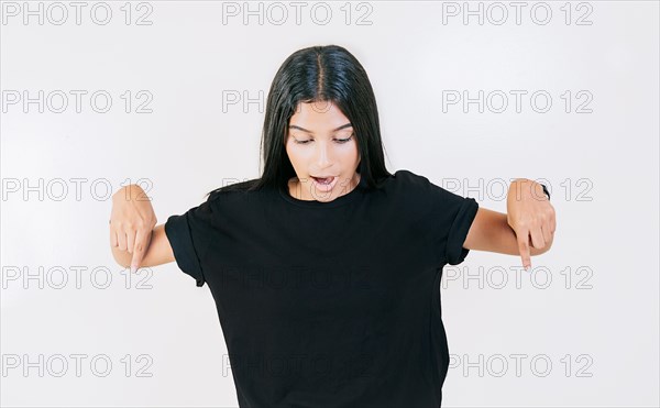 Amazed girl pointing at advertising down isolated. Surprised latin girl pointing blank space down