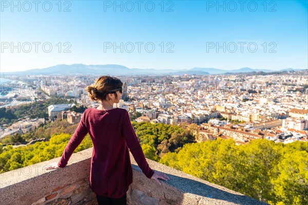 A young woman admiring the beautiful city from the wall of the Gibralfaro Castle in the city of Malaga