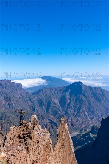 A young man after finishing the trek at the top of the volcano of Caldera de Taburiente near Roque de los Muchachos looking at the incredible landscape