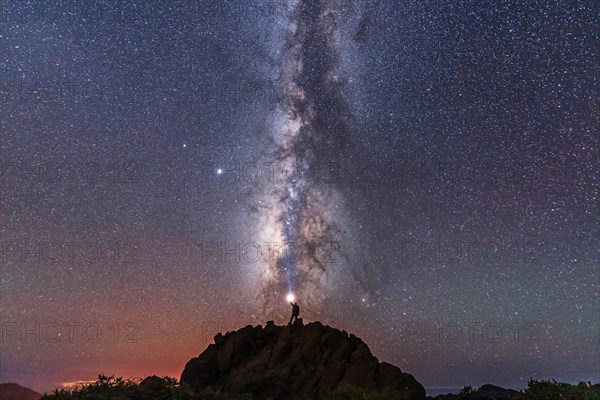 A young man with a flashlight below the beautiful milky way of the Caldera de Taburiente near the Roque de los Muchahos on the island of La Palma