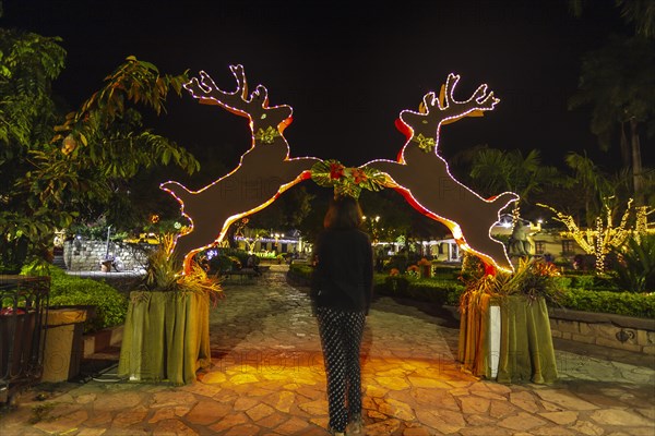 A young woman passing a reindeer arch at Christmas in Copan Ruinas. Honduras