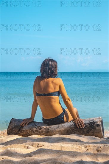 A young girl sitting in the sun on the beach of Punta de Sal