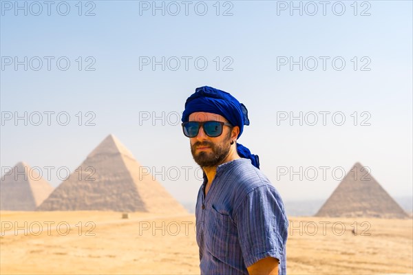 A young tourist wearing blue turban and sunglasses enjoying the Pyramids of Giza