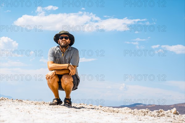 A young man crouched on his back on the white salt flat in Badwater Basin
