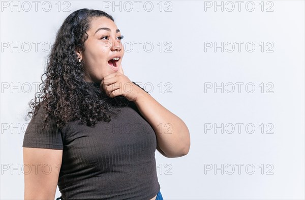 Surprised woman holding chin looking at an advertisement to side. Amazed latin woman with hand on chin looking at side isolated