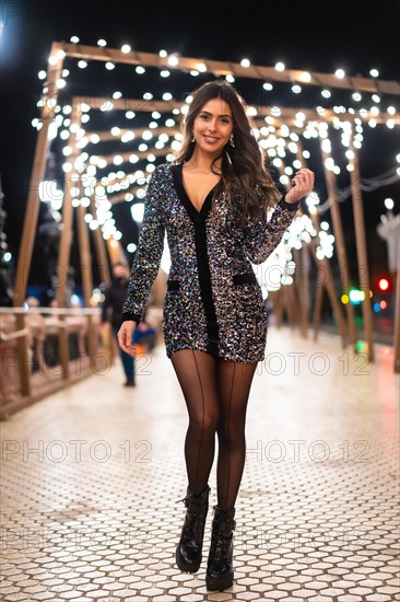 Winter lifestyle at Christmas. Brunette Caucasian girl in a fashionable sequined dress and black high heels