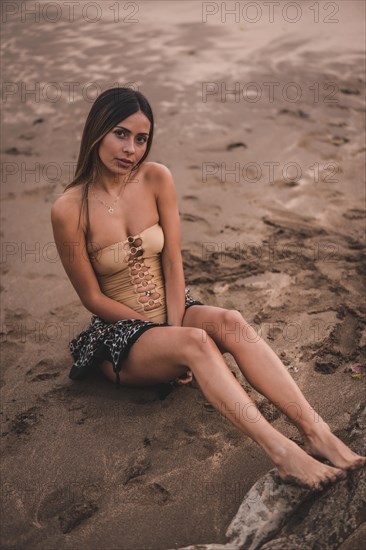 Fashion posing of a brunette woman in a swimsuit and a pareo on the beach in summer