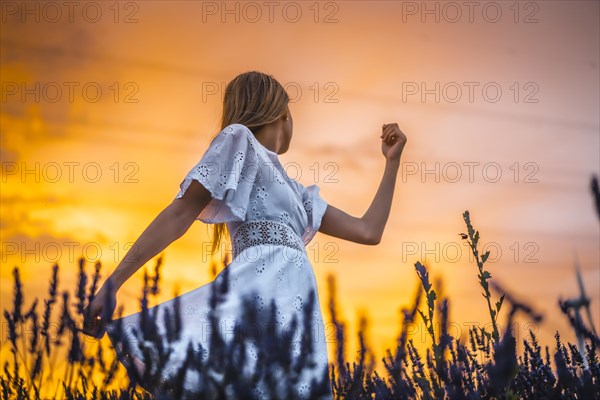 A young blonde Caucasian woman in a white dress in a cultivated lavender field in Navarra