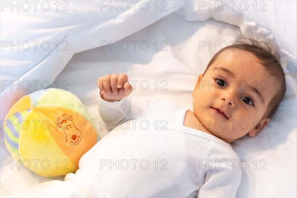 5 month old Caucasian baby smiling in white bed just woken up