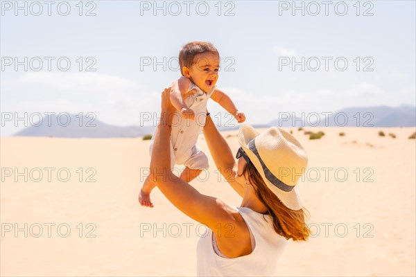 Young mother having fun with her son on vacation in the dunes of Corralejo Natural Park