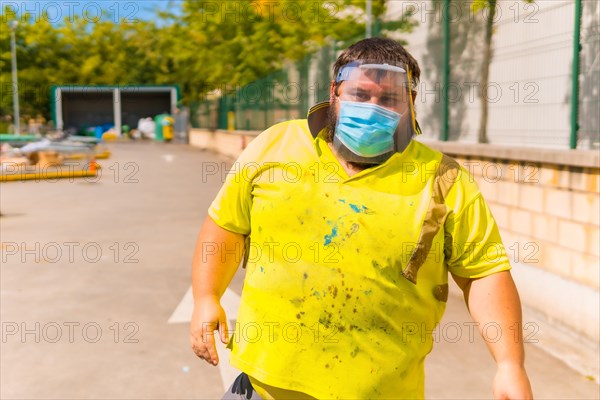 Worker in a recycling factory or clean point and garbage with a face mask and plastic protective screen