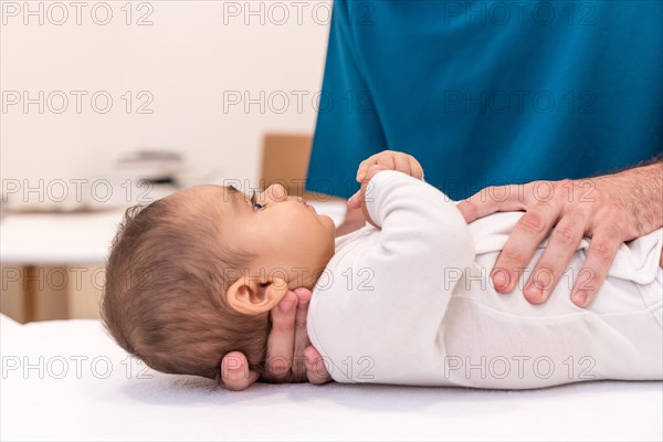 Close-up photo of an unrecognizable doctor examining baby in office