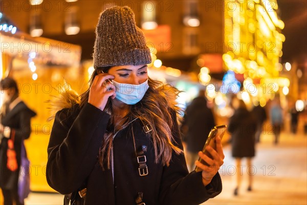 Christmas lifestyle in a new normal. Young girl with face mask visiting the Christmas market in the coronavirus pandemic