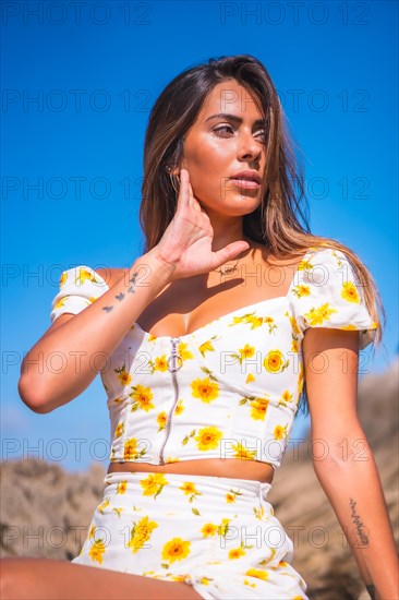 Portrait of a young woman in a white dress on the beach enjoying the summer