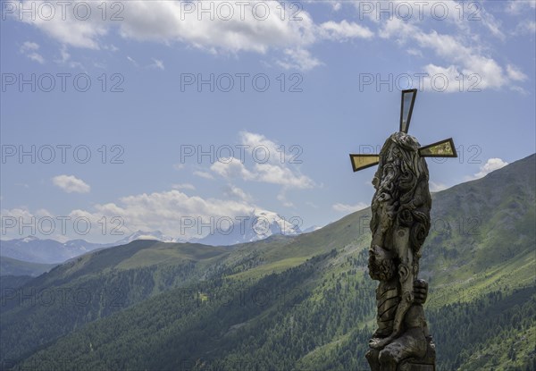 Wooden sculpture Four-man column behind it the Ortler