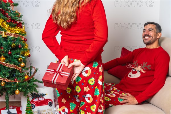 Young couple sitting by the Christmas tree
