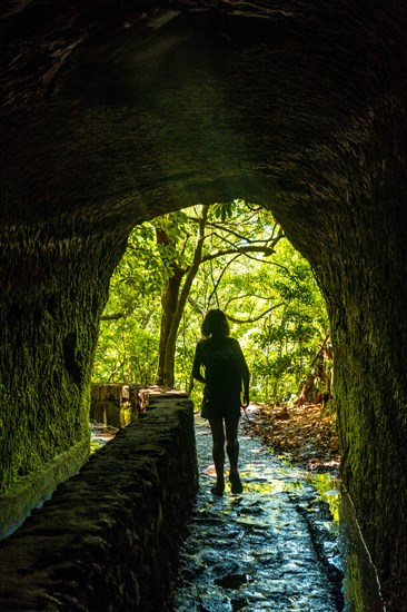 Silhouette of a young woman in the cave at Levada do Caldeirao Verde