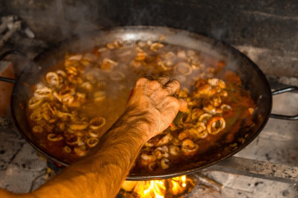 Adding saffron to the Valencian paella with embers and vegetables. Traditional Spanish food