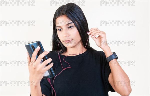 Latin girl enjoying music with phone isolated. Portrait of beautiful girl listening to music with smartphone isolated. Happy latin gir listening to music with cell phone isolated