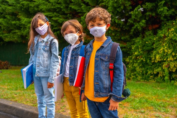 Three brothers with face masks ready to go back to school. New normality